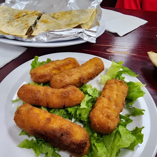 Fried cheese sticks on lettuce with quesadillas wrapped in foil in the background at Gyro Queen.