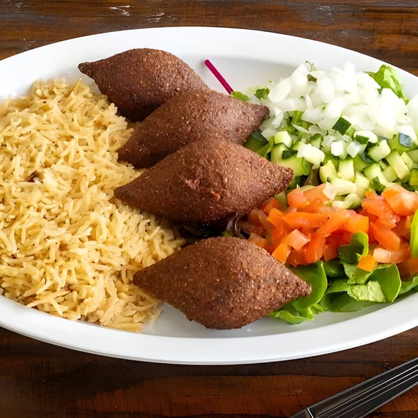 Gyro Queen's Mediterranean plate with four kibbeh, rice, and a fresh salad with tomatoes, cucumbers, and onions.